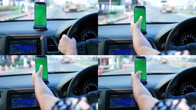 女人在路上开车，使用绿屏智能手机。看地图或听音乐。