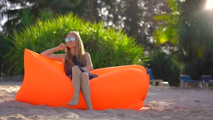 热带海滩上的年轻女子坐在充气沙发上。暑假概念