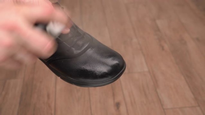 一名男子在皮靴上喷洒防水气溶胶喷雾。擦鞋。鞋护理产品的使用