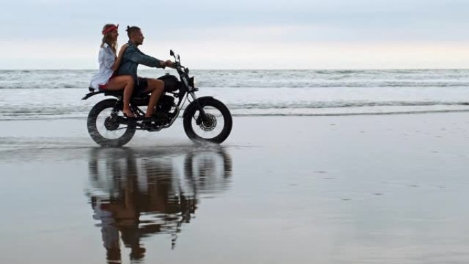 年轻漂亮的情侣潮人在海滩上骑复古摩托车，户外肖像，骑男孩和女孩，一起旅行，海洋，海洋
