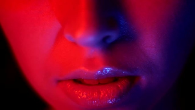 在夜总会拍摄红色霓虹灯和bokeh背景的漂亮女性嘴唇的特写镜头