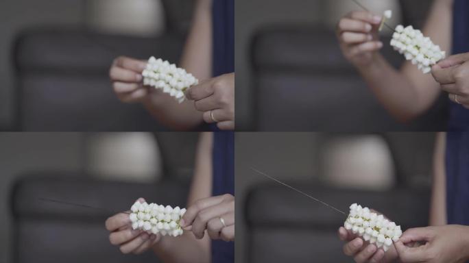 年轻女子的手正在用白色栀子花制作美丽的花环。