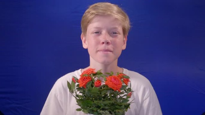 12岁的男孩在摄影棚里用蓝色色度键向相机献花。