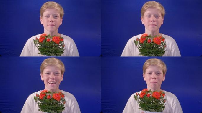 12岁的男孩在摄影棚里用蓝色色度键向相机献花。