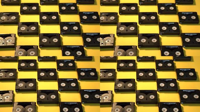 老式迷你DV盒式磁带，用于一天内拍摄。黄色背景上的塑料录像带制成的图案