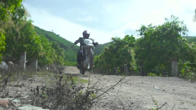 摩托车骑手在乡村道路上后轮行驶。骑在后轮上的摩托车手。摩托运动和旅行。摩托车生活方式。极端蜱