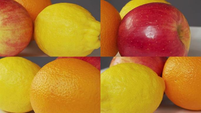 新鲜水果的近景。旋转背景。安装红苹果、黄色柠檬和橙色。热带水果静物。选择性软聚焦。背景模糊