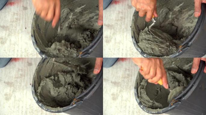 当高级男子瓷砖手自己用木桶搅拌水泥时，桶中的特写镜头