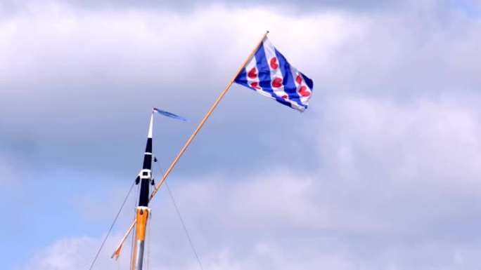 在一个有风的夏天，在一艘经典帆船的桅杆顶部的弗里斯兰旗
