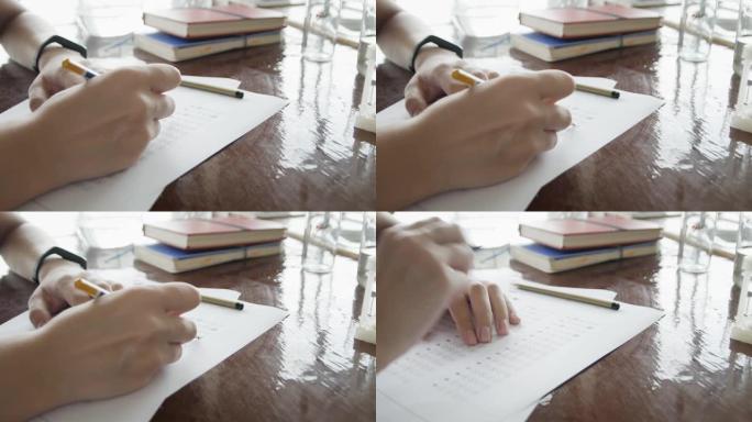 学校/大学的学生在化学教室里用手拿铅笔在光学表格上写试卷，在桌子上做期末考试。