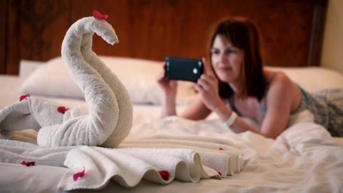 女孩在电话上拍了一张用毛巾制成的天鹅的照片