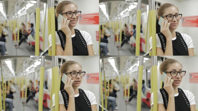年轻女子在地铁里用智能手机说话。
