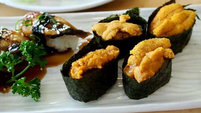 日本料理，寿司套装 (鳗鱼寿司、海胆寿司、鱿鱼寿司) 放在白盘上。平移对。