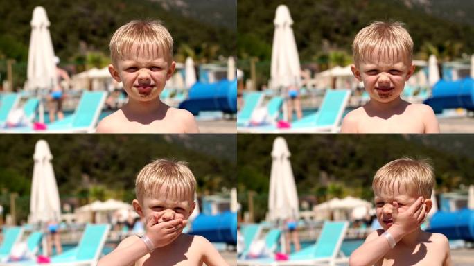 暑假，一个小孩在游泳池附近吃巧克力冰淇淋。