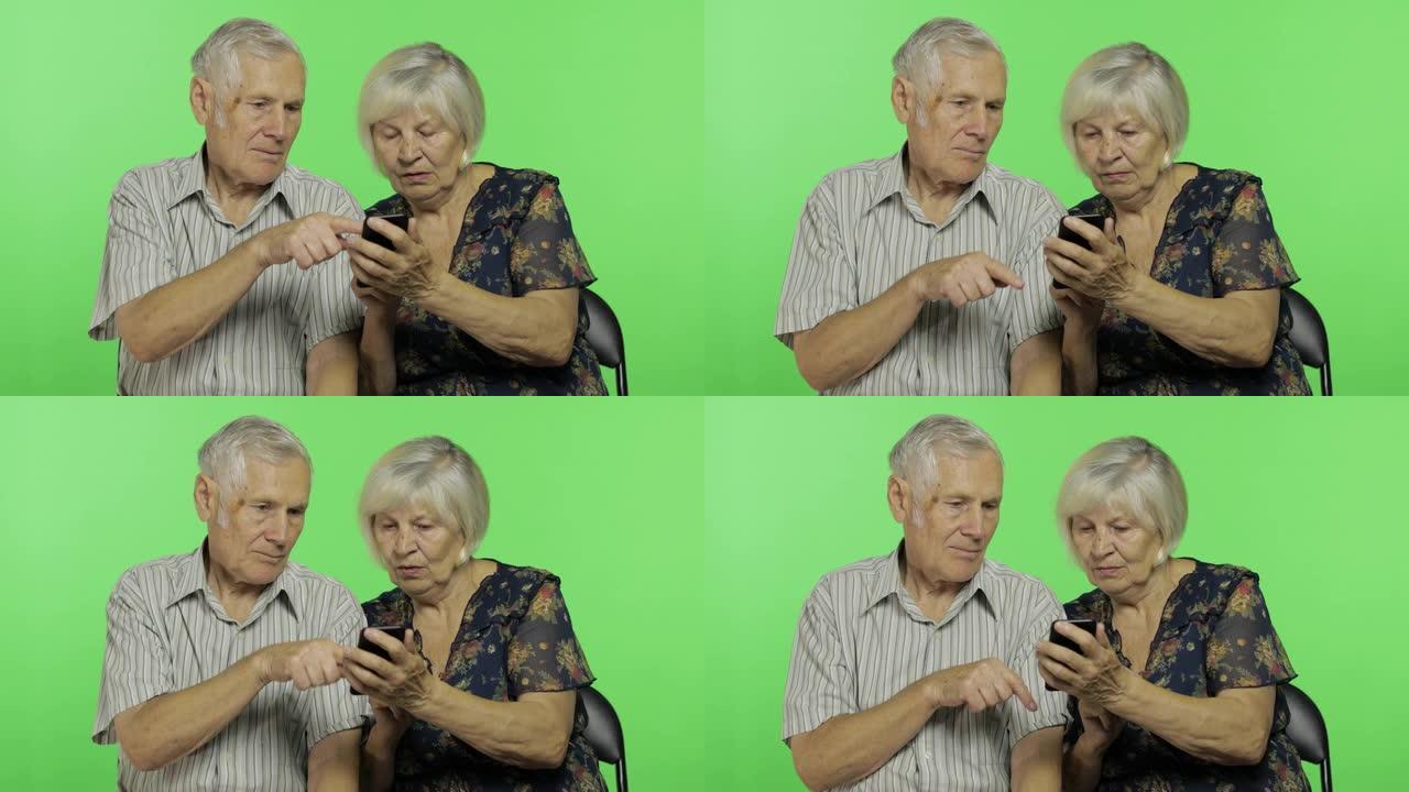 老年男女坐在一起，在智能手机上工作。色度键