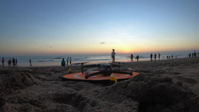 这架无人机正准备在日落日在海洋附近的海滩上起飞。
