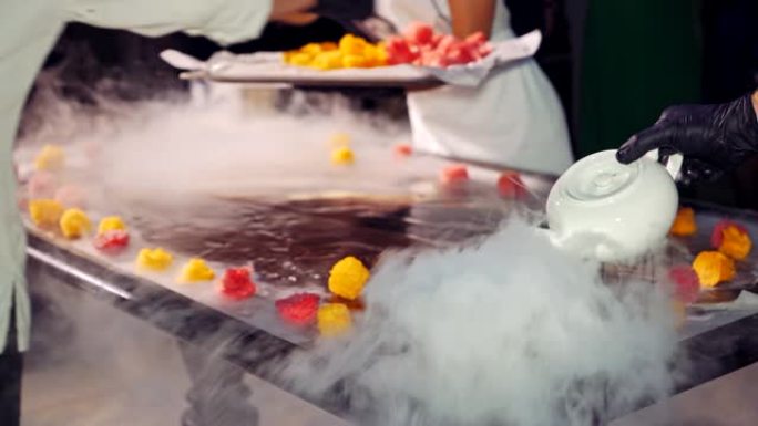 厨师和他的助手正在用蒸汽将水果放在冰淇淋的背景上。