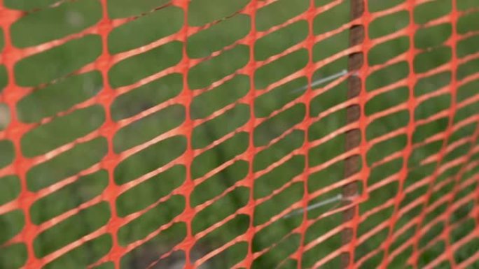花园中的橙色篱笆绿草的背景。特写。摄像机沿着栅栏移动