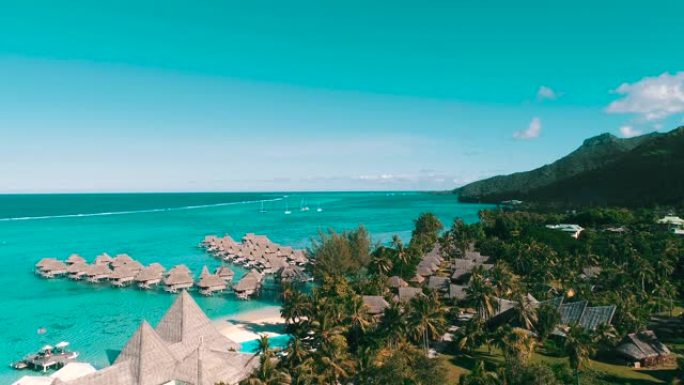 在法属波利尼西亚天堂岛的蓝色泻湖上的高跷上的房子。酒店客房非常适合浪漫的假期和棕榈树下的黄金海滩旅游