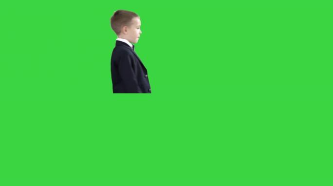 穿着经典深蓝色商务服装的男孩在绿色屏幕上走过，色键