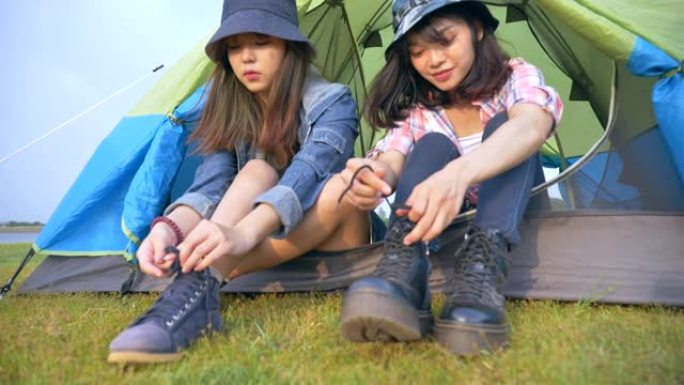 亚洲背包客的场景慢动作在暑假期间，在湖边的帐篷前系紧鞋带。他们在假期里很开心，很开心，很放松。青少年