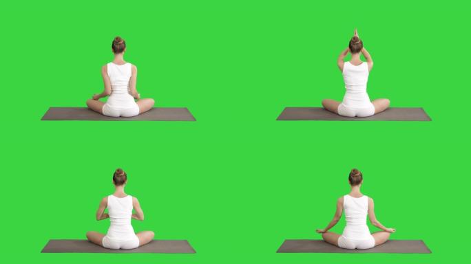 平静的漂亮女人做瑜伽锻炼坐在瑜伽姿势在一个绿色屏幕，色度键