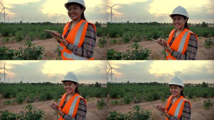 场景慢动作工程师亚洲妇女使用平板电脑评估风力涡轮机，可再生能源工厂的概念