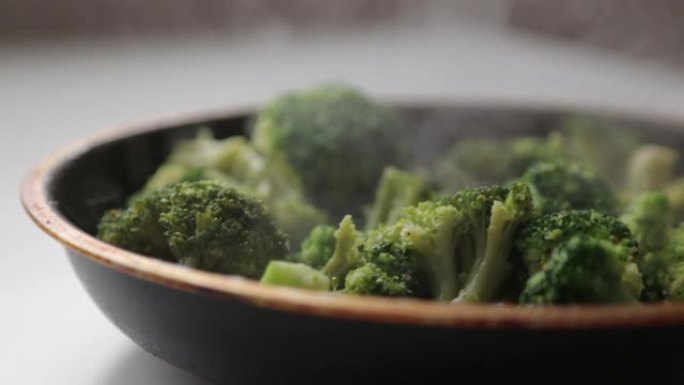 卷心菜西兰花放在平底锅里，里面有油和香料。烹饪新鲜的绿色卷心菜产生的蒸汽和烟雾。