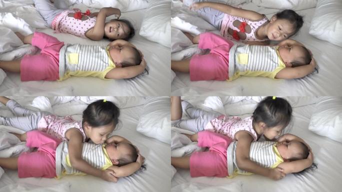大姐姐亲吻她的孩子，表达爱意。躺在床上的亚洲女孩。叫醒躺在床上的姐妹们。