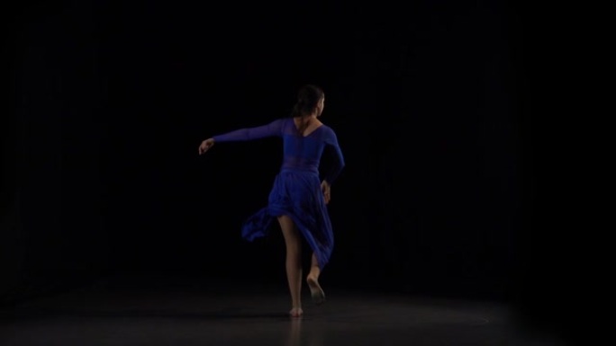 性感的芭蕾舞演员在工作室的黑色背景下跳舞。慢动作