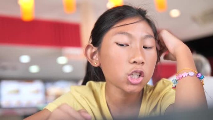 快乐的亚洲女孩在餐厅为她的订单阅读菜单。