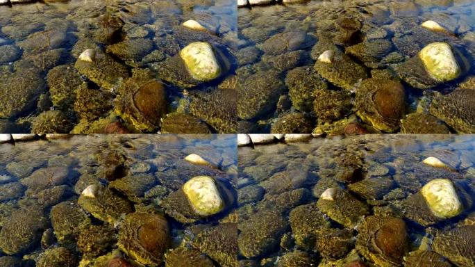 在晴朗的日子里，清澈的水流在石头上的特写镜头，水在运动中闪烁。