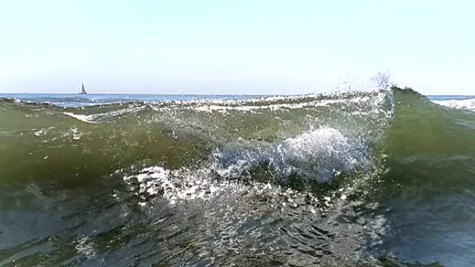 大微风以慢动作靠近，向岸边移动。波浪的浪花在阳光下闪闪发光，慢慢地倾泻，互相撞击，落在水面上。