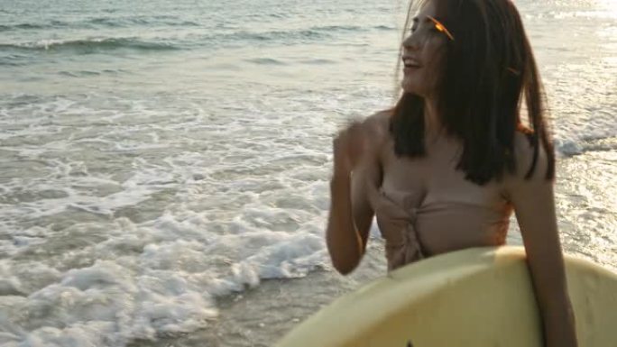 泰国美丽大海的海滩上，亚洲少女手持冲浪板。