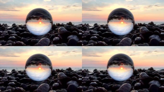 石头上水晶球内的美丽日落反射，水面上的太阳，海滩，风景