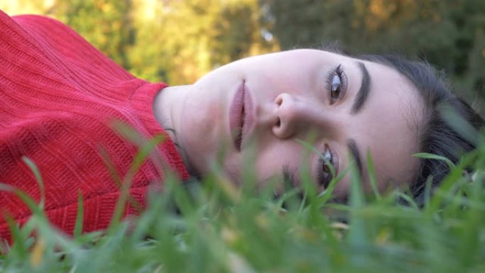 梦见美丽的年轻女子躺在草地上，睁开眼睛，看着相机