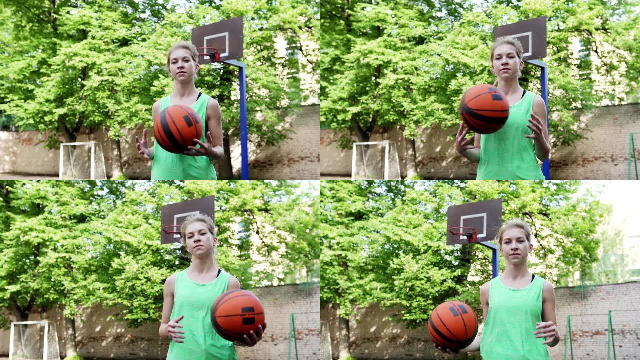 自信的女篮球运动员以慢动作将球从一只手扔向另一只手，站在室外球场上看着相机