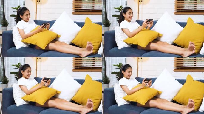 坐在沙发上的亚洲女性在家中使用手机在线感到不寒而栗。数字时代的生活方式