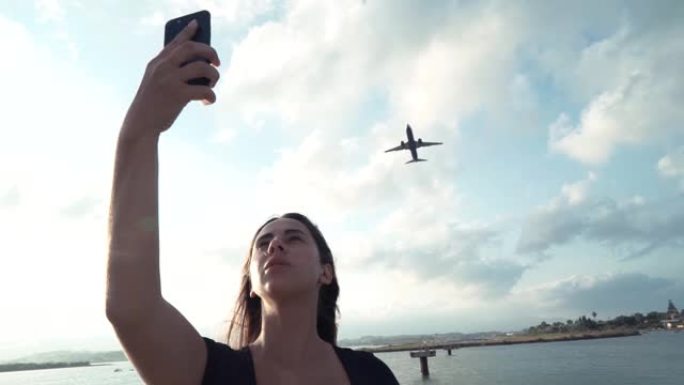 美丽的女孩在手机上与飞机自拍。旅行女孩博客