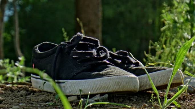 一双鞋在夕阳的草地上的污垢