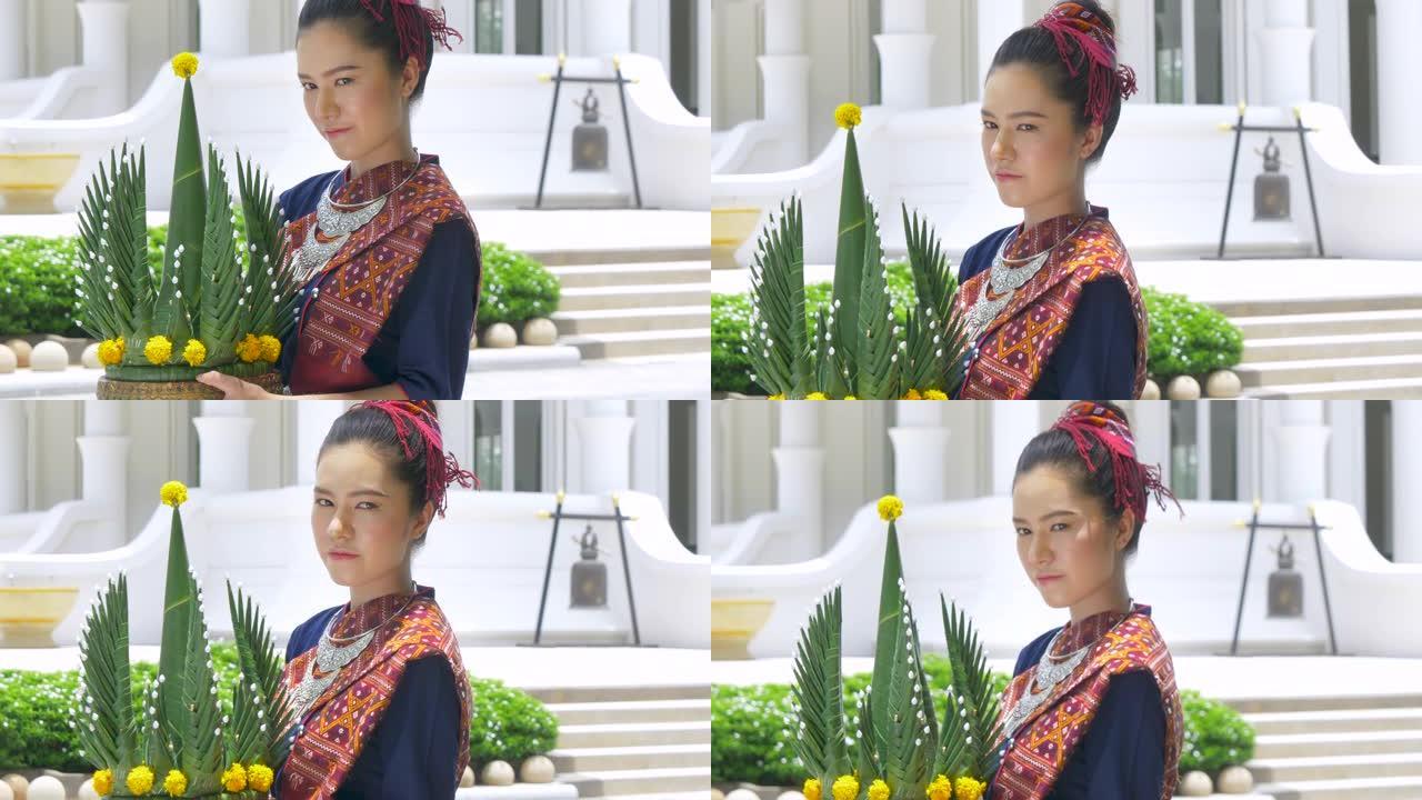 泰国年轻女子穿着泰国民族服装套装拿着花盘。欢迎来到泰国概念。