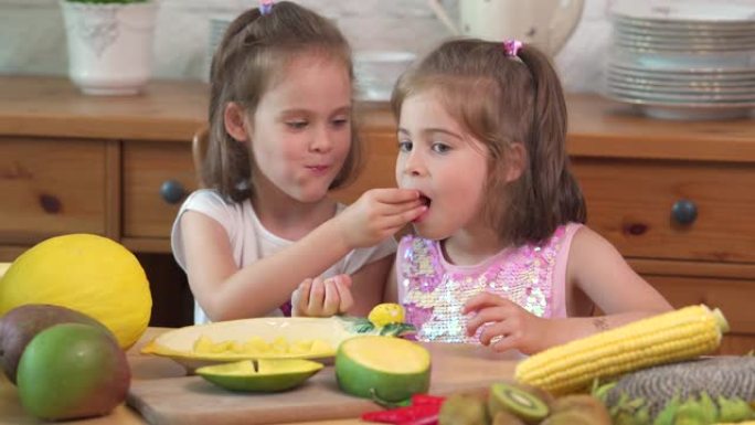 两个可爱的女孩在笑着吃多汁的黄色芒果