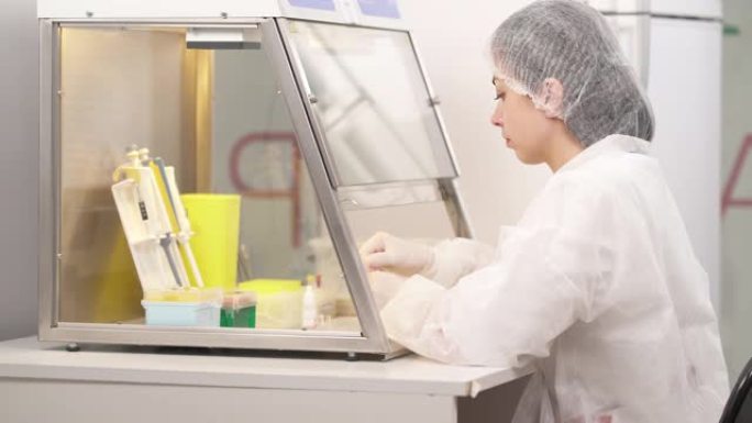 医学实验室科学家在层流柜中进行微生物试验的侧视图。科学保健研究理念