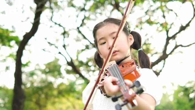 亚洲小女孩拉小提琴。乐器的概念，自我学习和生活体验。4K分辨率和慢镜头。