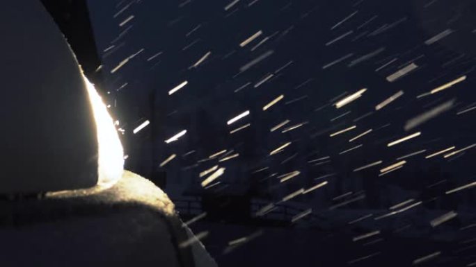 夜间在雪地里拍摄汽车的特写镜头。大雪花正在飘落，糟糕的天气。
