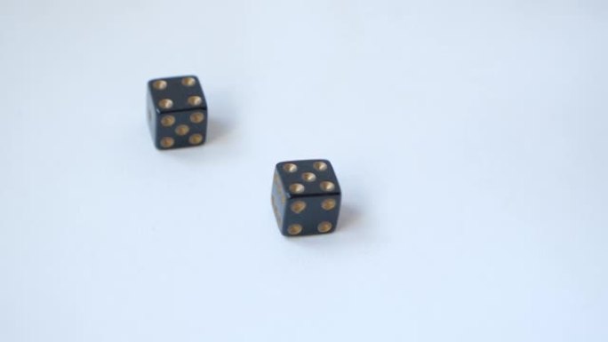 用一对黑色赌博骰子在白色桌子上慢动作滚动一个五和一个四