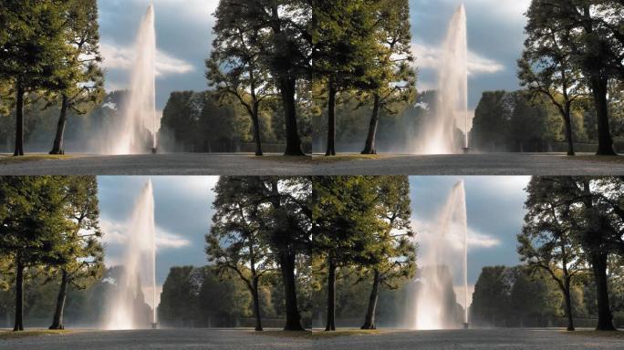 德国汉诺威。巨大的高喷水器从放在地上的碗中倒出。在公园绿树的背景下。慢动作