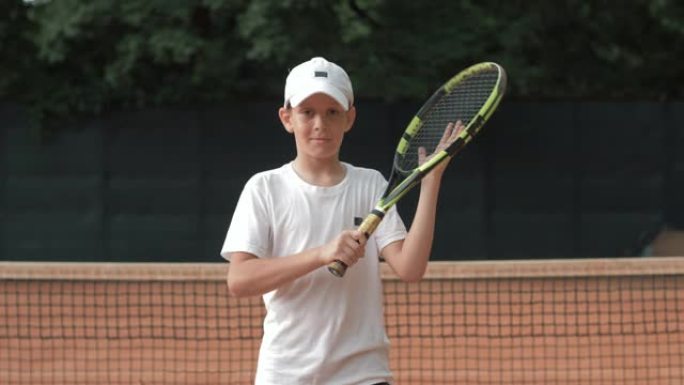 网球运动员少年男孩的肖像手握球拍，在球场上具有竞争精神