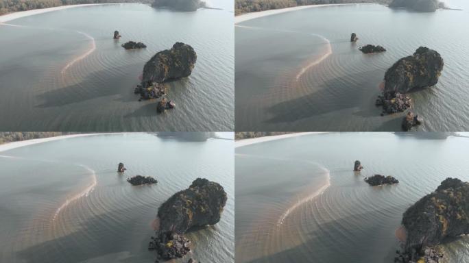 无人机的飞行沿着丹戎茹海滩，在马六甲海峡，你可以看到沙子吐在海里，水面上的波浪，破碎在岩石上。