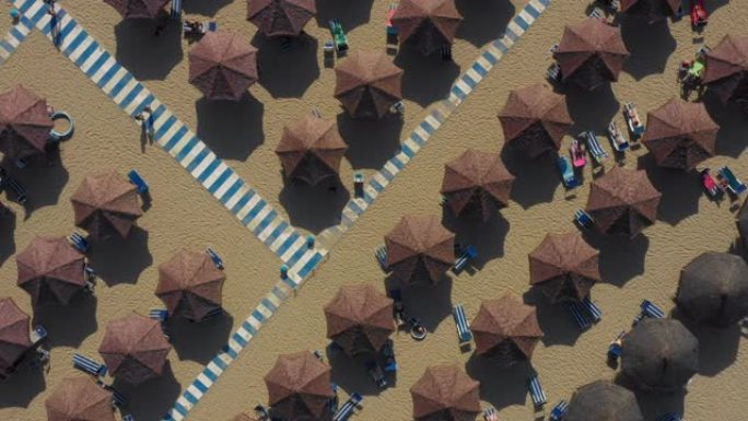 意大利海滩上成排的沙滩伞，泳客和条纹人行道的180度无人机镜头。